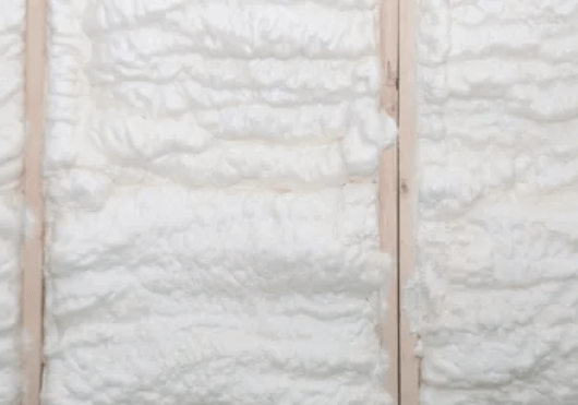 Spray foam insulation between wooden wall studs.