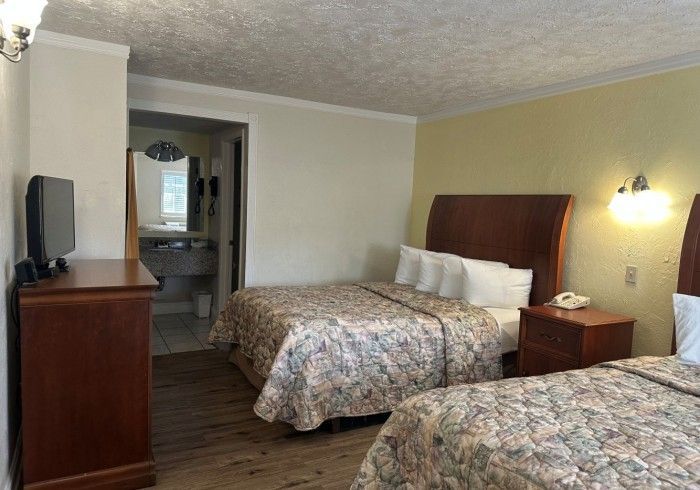 Two twin beds in a motel room, brown furniture, floral bedspreads, bathroom visible.