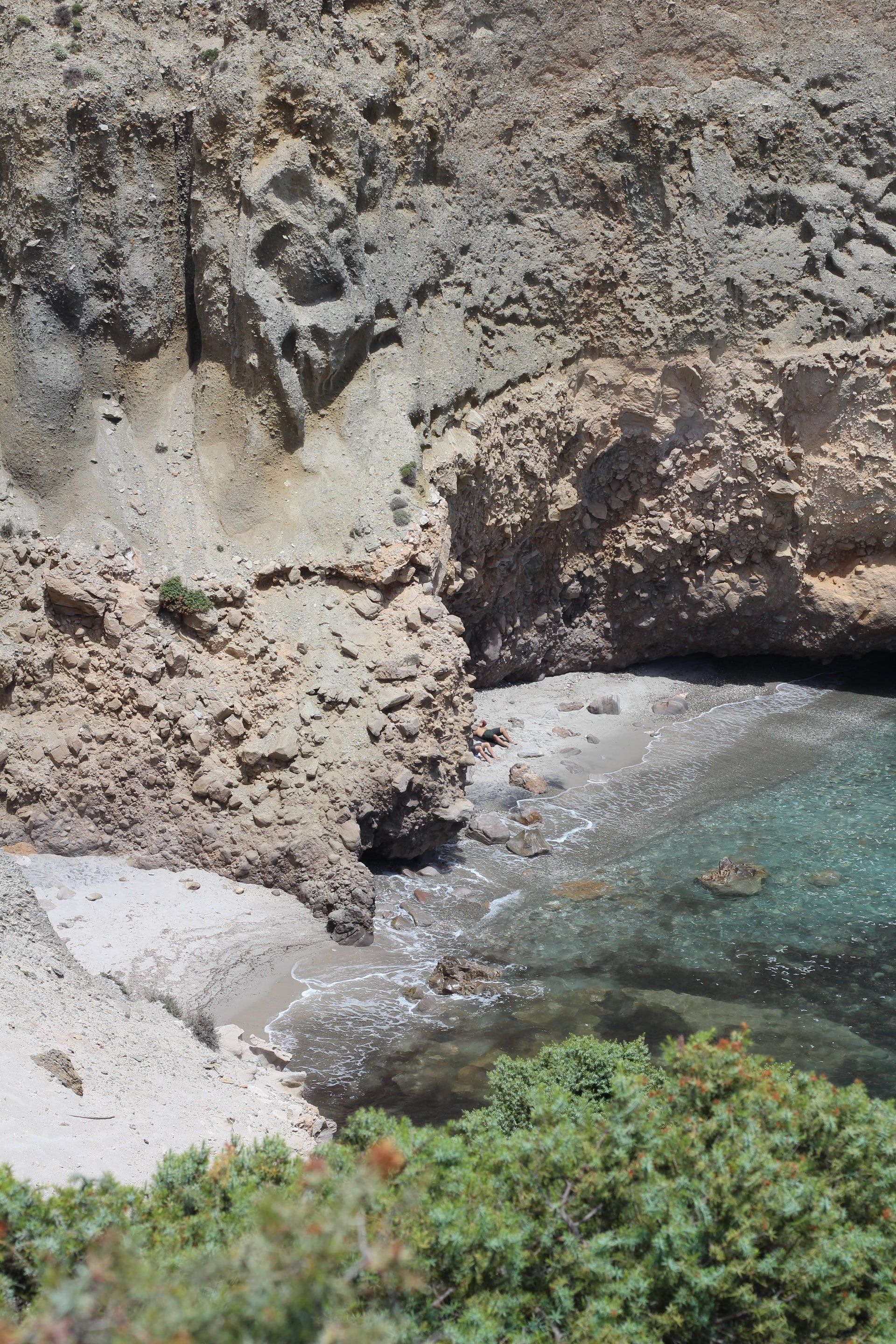 Rocky cove with clear turquoise water and a small sandy beach.