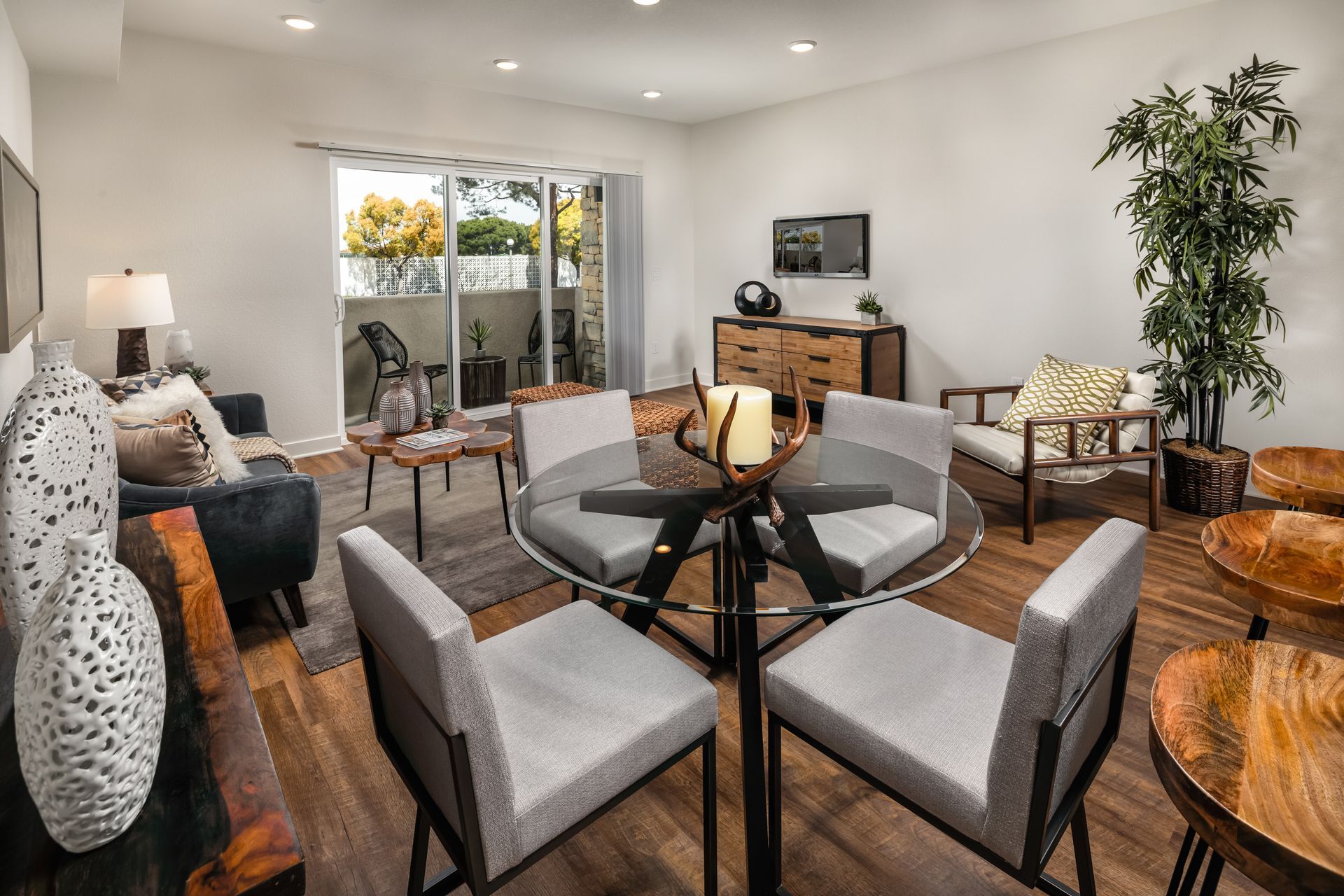 A living room with a dining table and chairs and a sliding glass door.