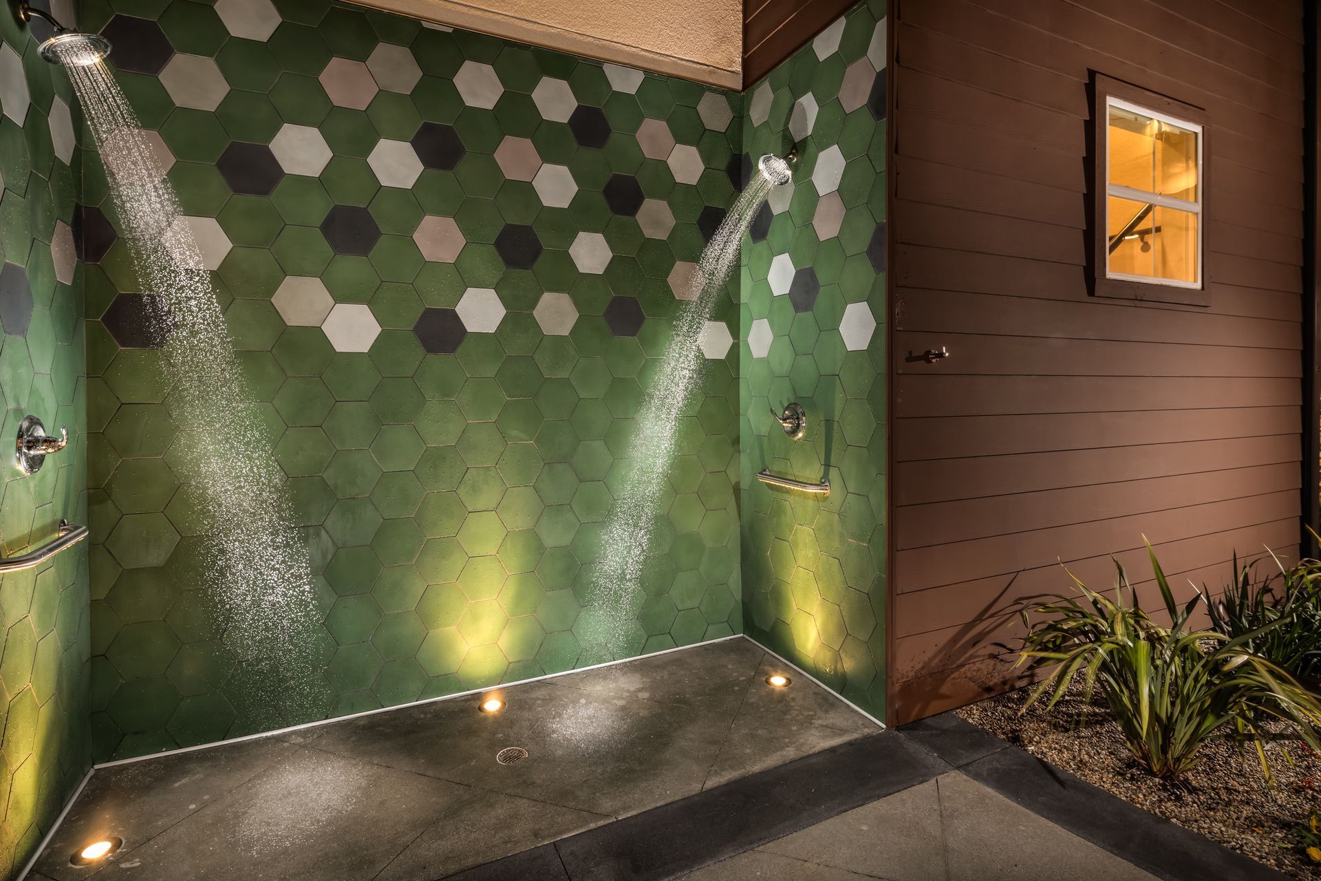 A shower with green tiles on the wall and a window.