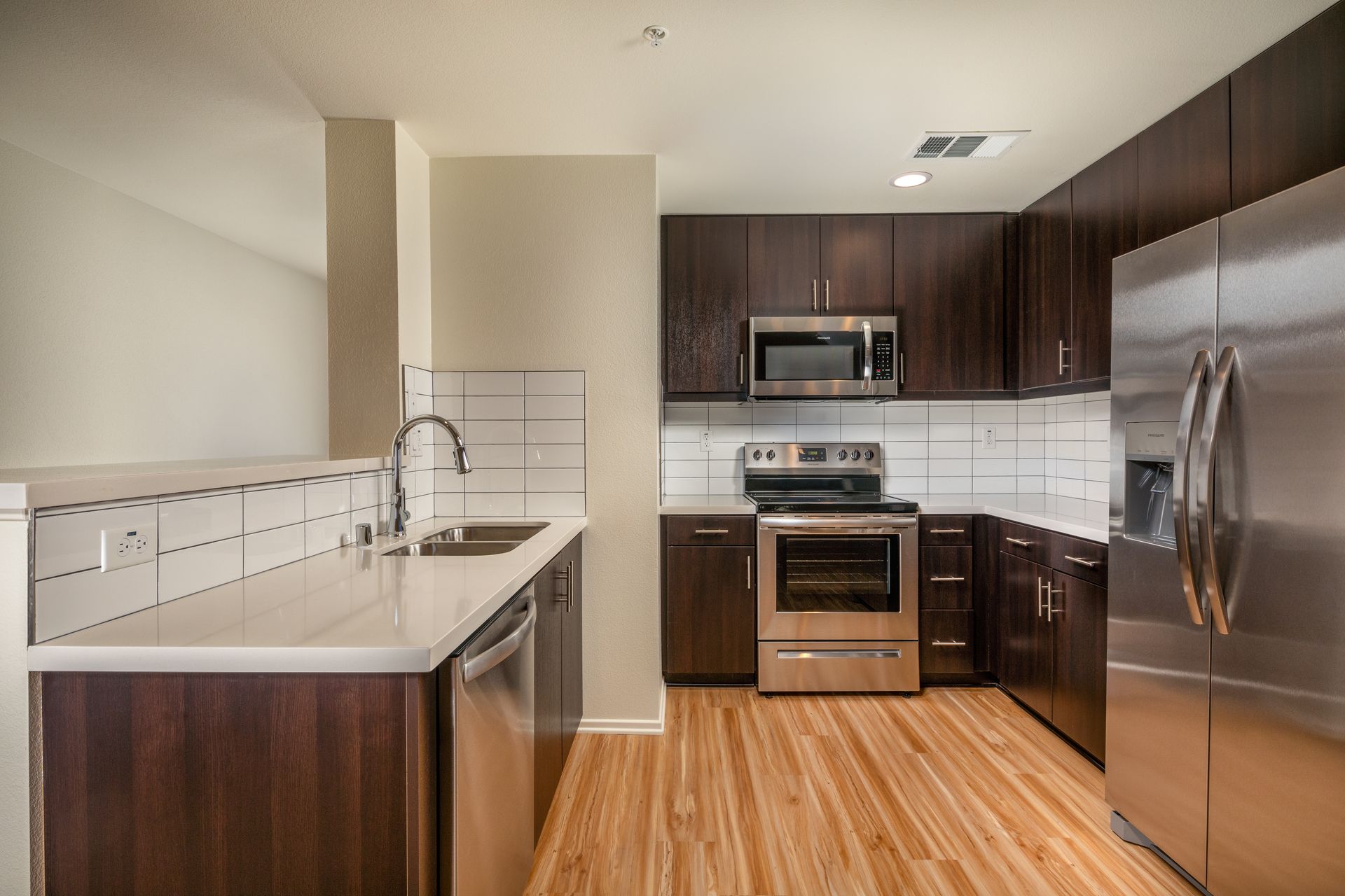 A kitchen with stainless steel appliances and wooden floors.