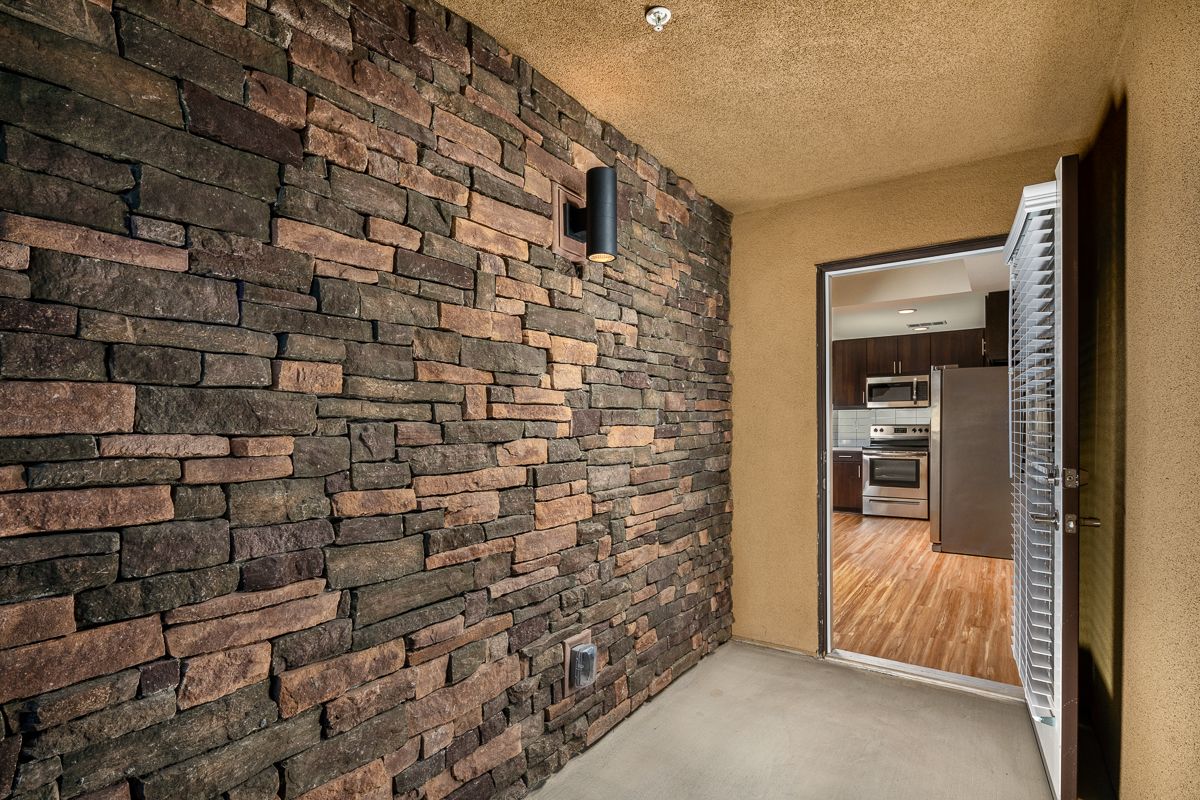 A room with a brick wall and a door leading to a kitchen.