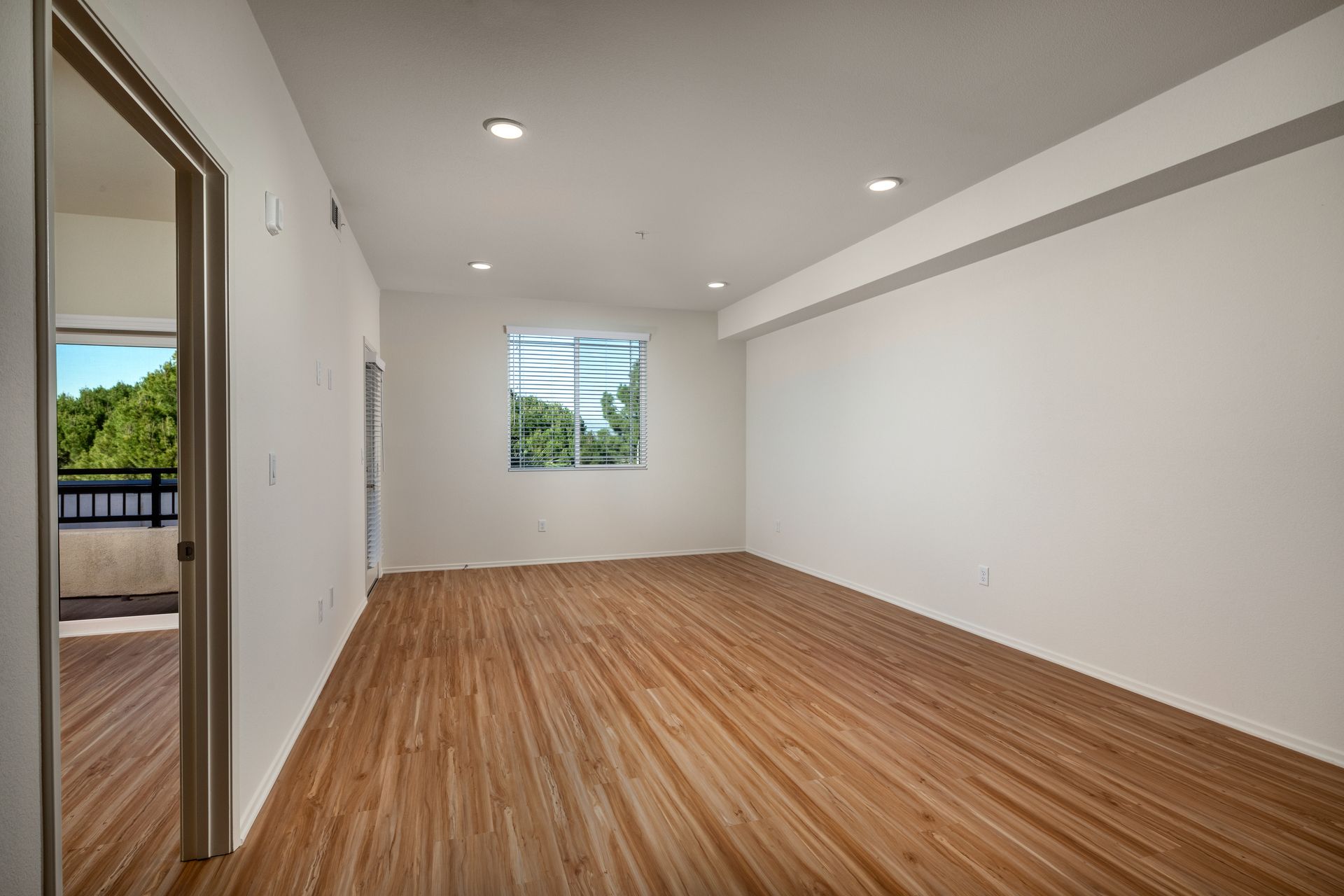 An empty living room with hardwood floors and white walls.