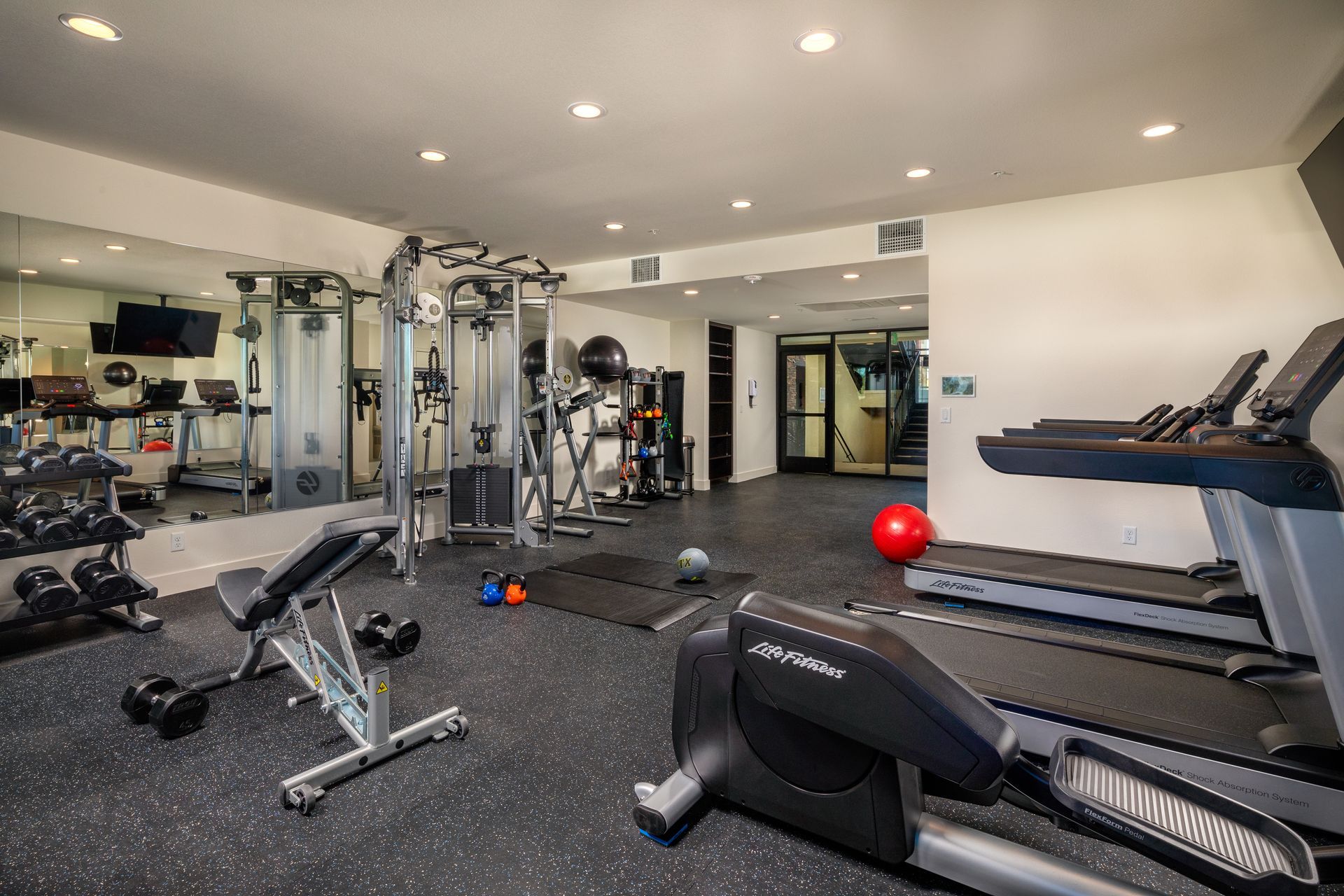 A large gym with a lot of equipment and a large mirror.