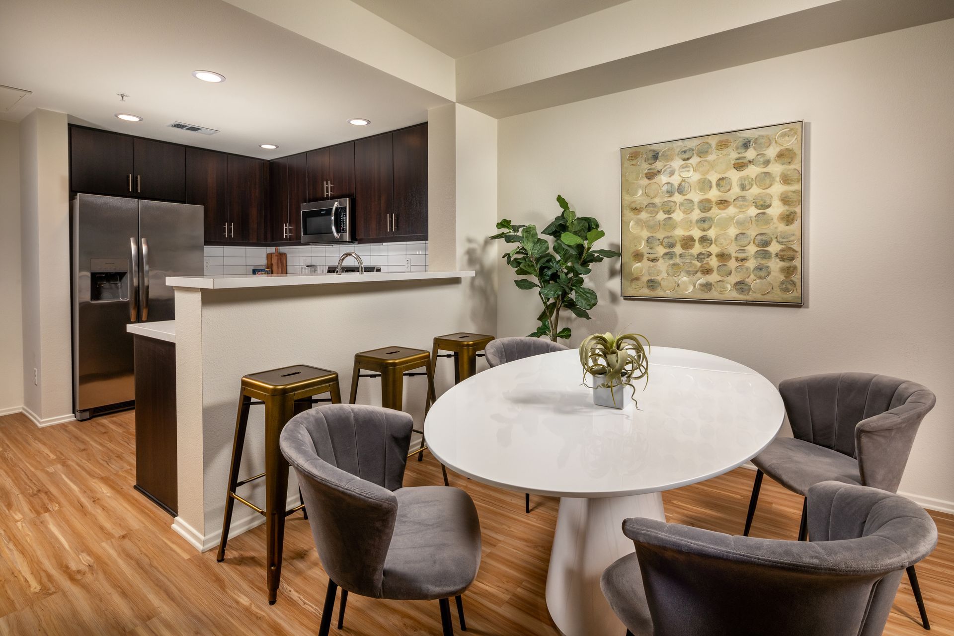 A dining room with a round table and chairs next to a kitchen.