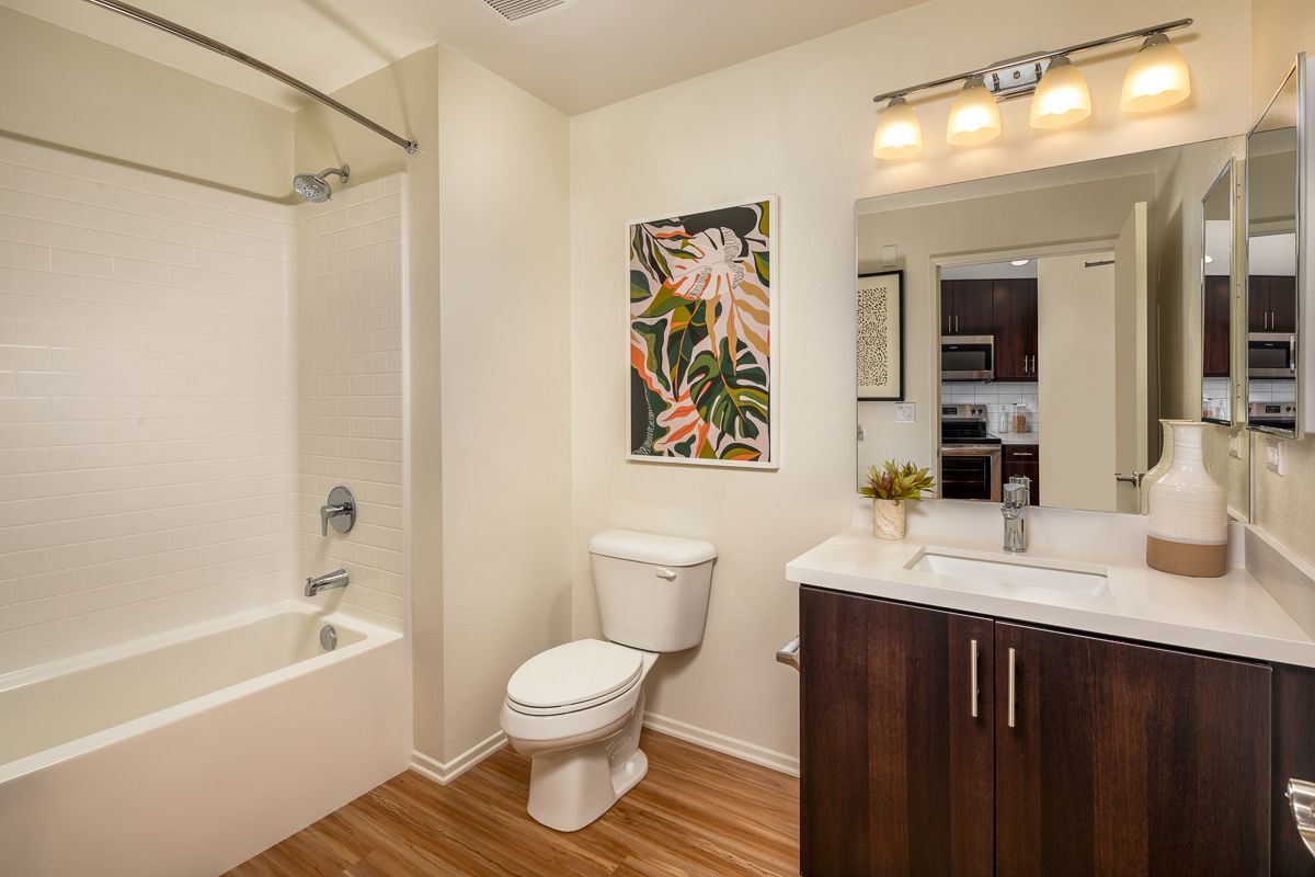 A bathroom with a toilet , sink , bathtub and mirror.