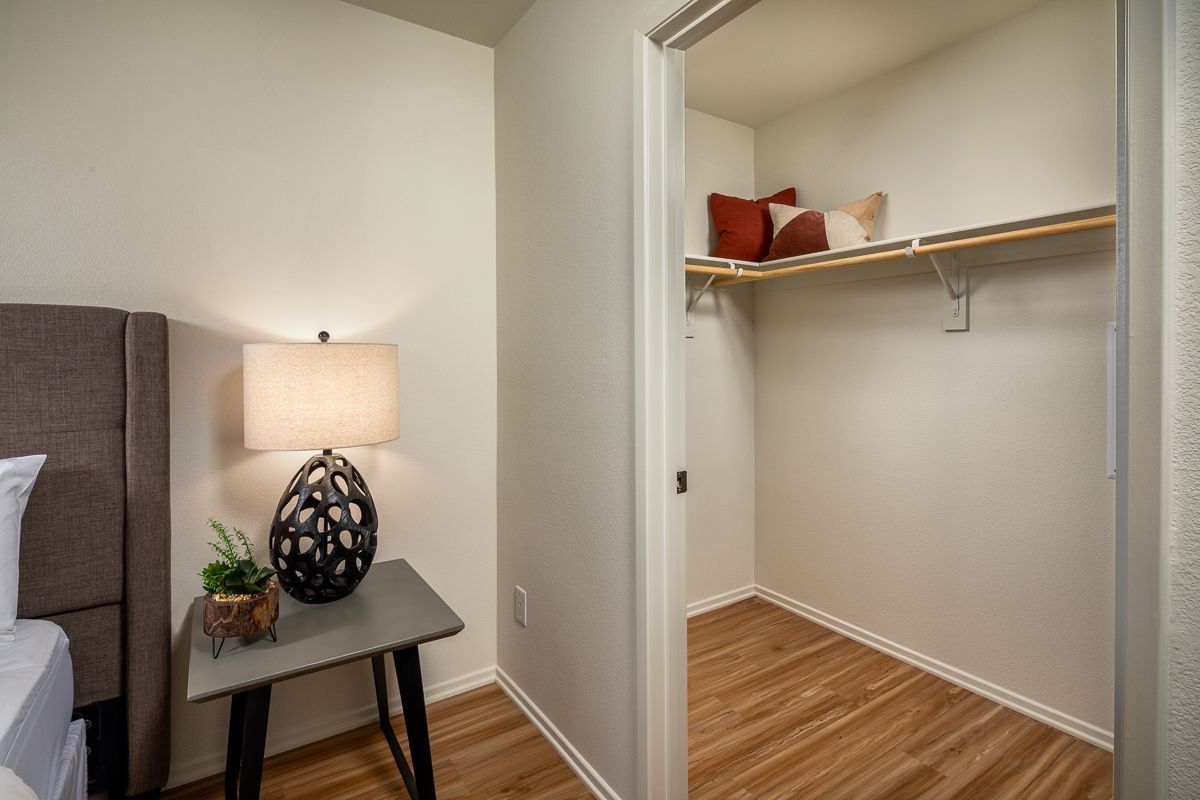 A bedroom with hardwood floors and a walk in closet.