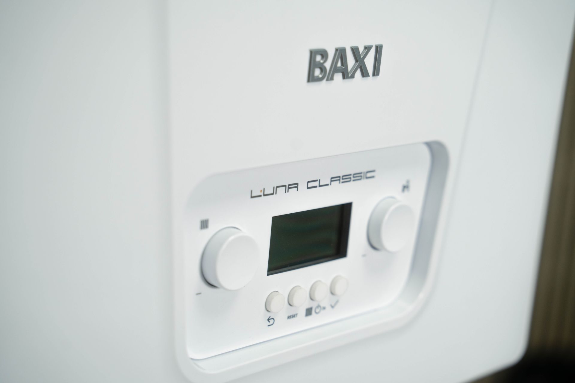 Primo piano del pannello di controllo bianco della caldaia Baxi Luna Classic con manopole, display e pulsanti.