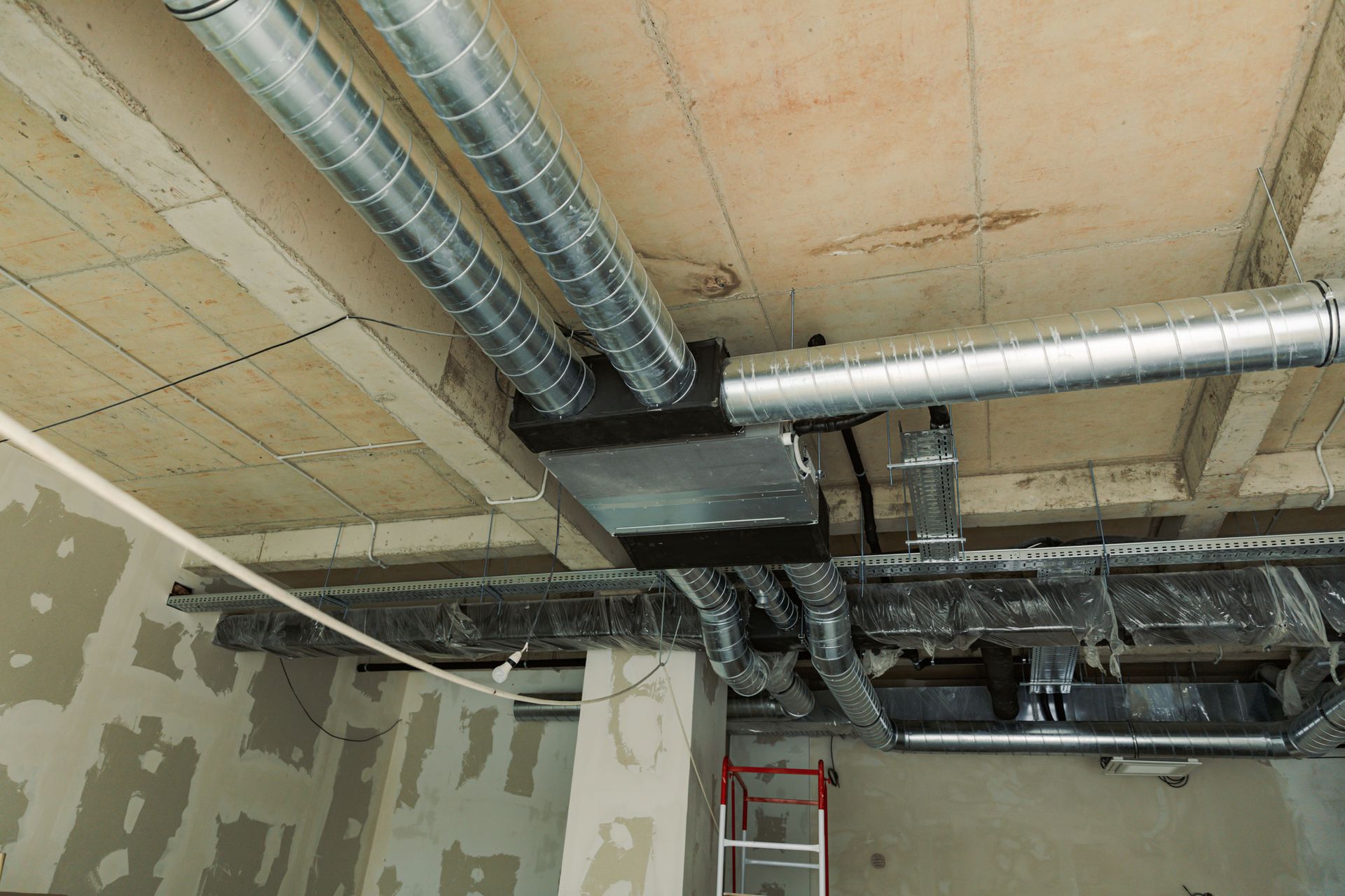 Un uomo che indossa guanti arancioni sta lavorando su una presa elettrica con un cacciavite.