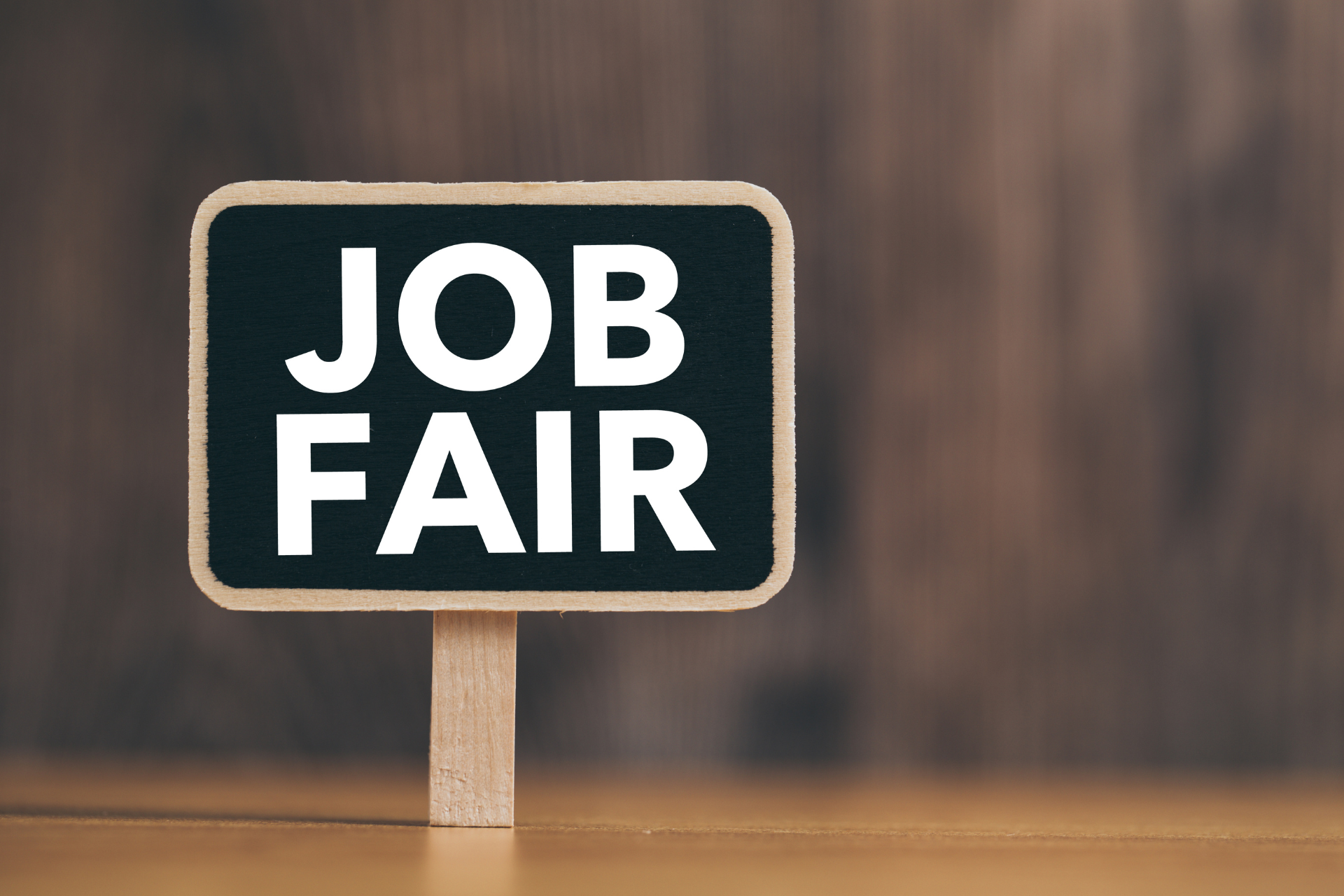 A wooden sign that says `` job fair '' on a wooden table.
