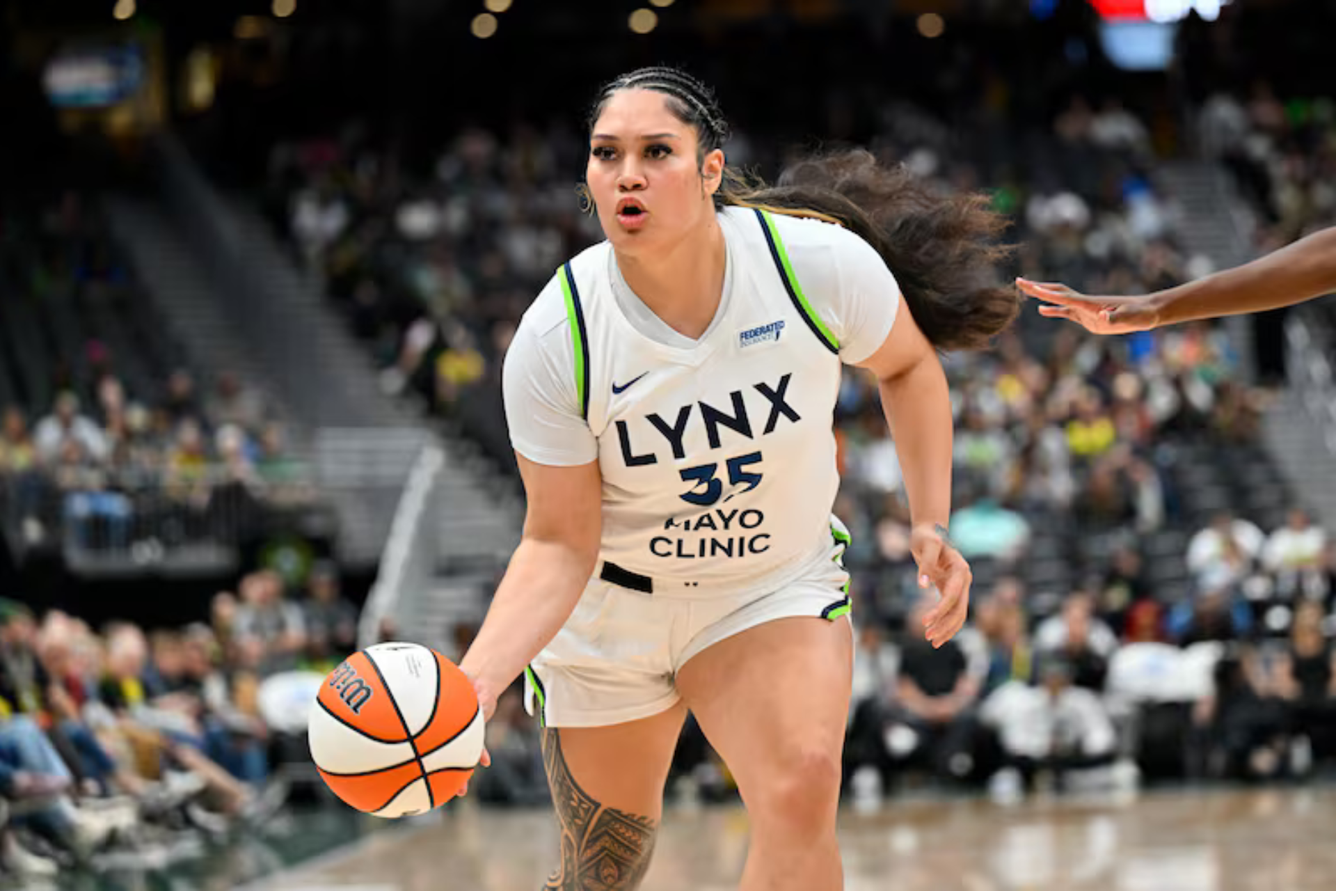 A woman is dribbling a basketball on a basketball court.