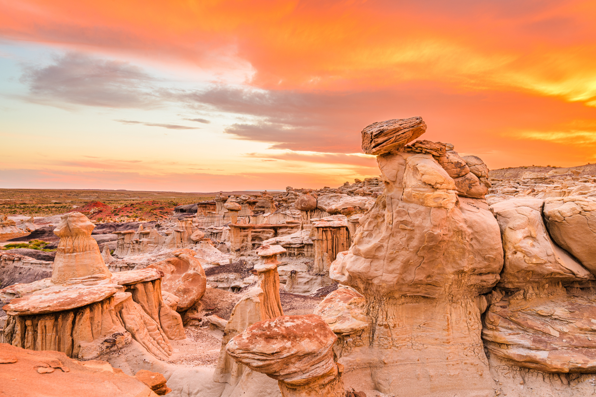 A desert landscape with rock formations and a sunset in the background.