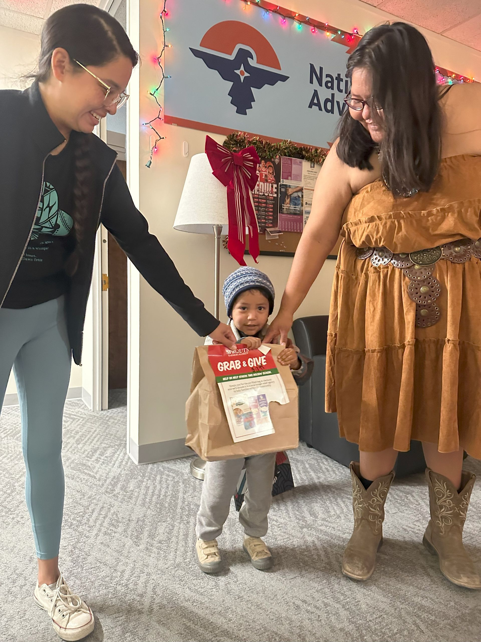 Two women are standing next to a little boy in a native american costume.