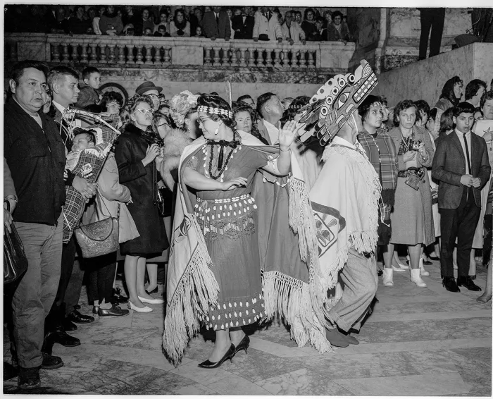 A black and white photo of people dancing in front of a crowd
