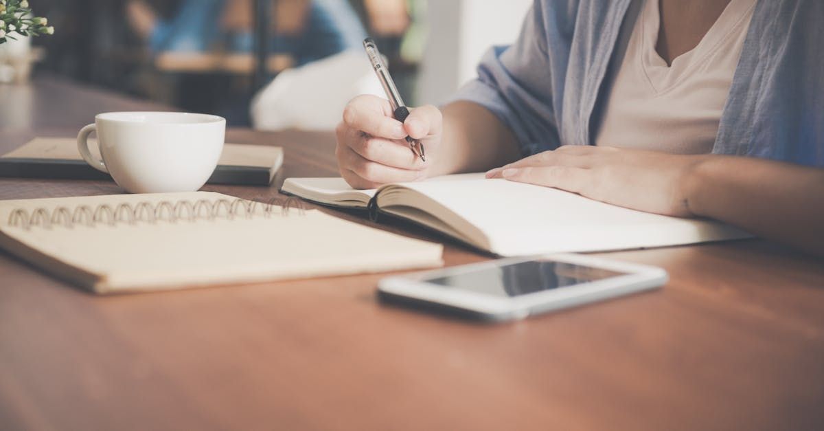 A woman is sitting at a table writing in a notebook.