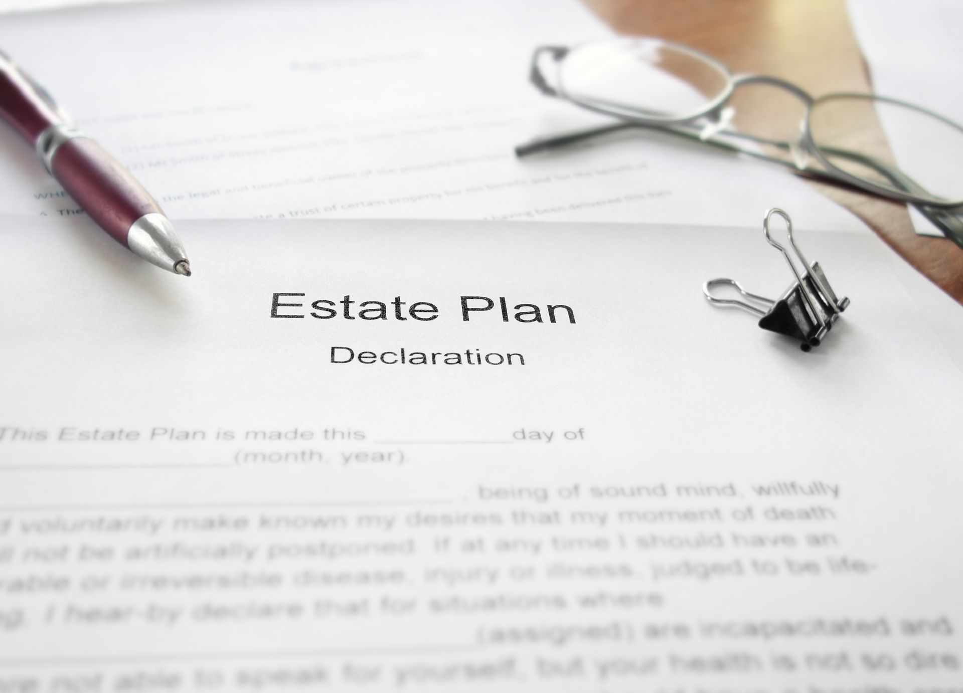 Estate plan document with pen, glasses, and binder clip on a desk