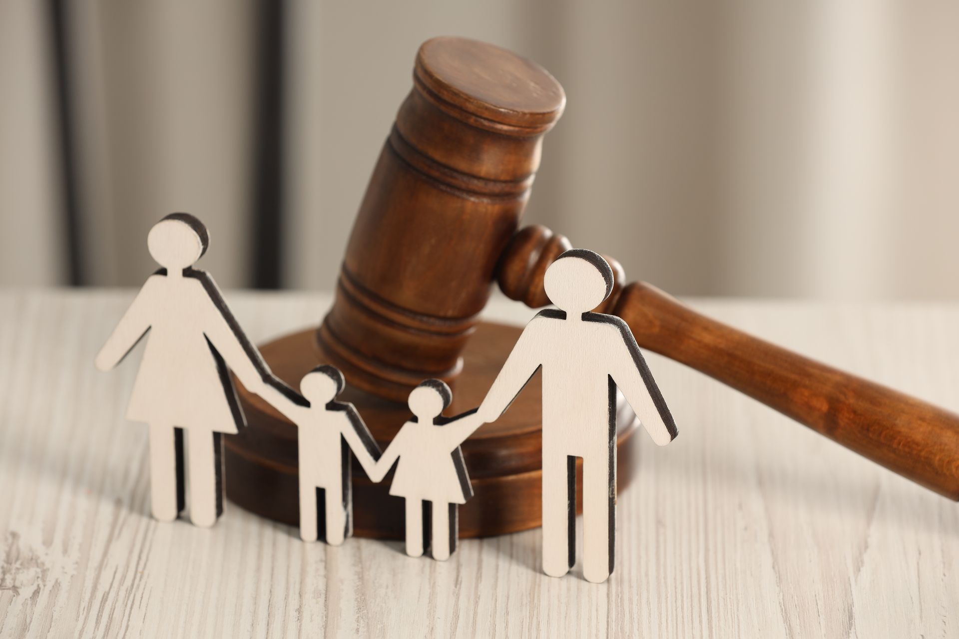 Paper family silhouettes in front of a judge’s gavel on a table, symbolizing family law or custody.