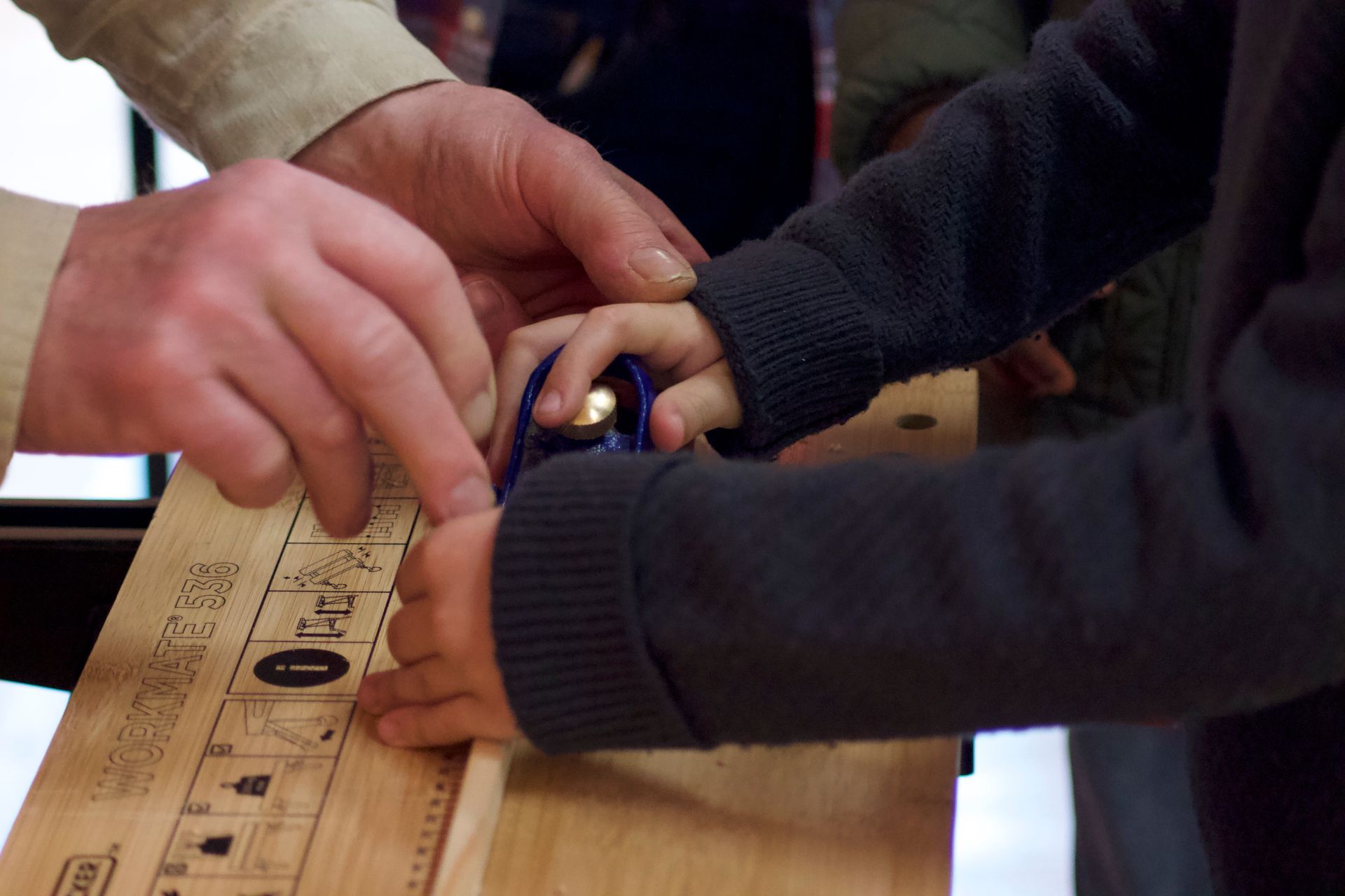 A person is cutting a piece of wood with a pair of scissors