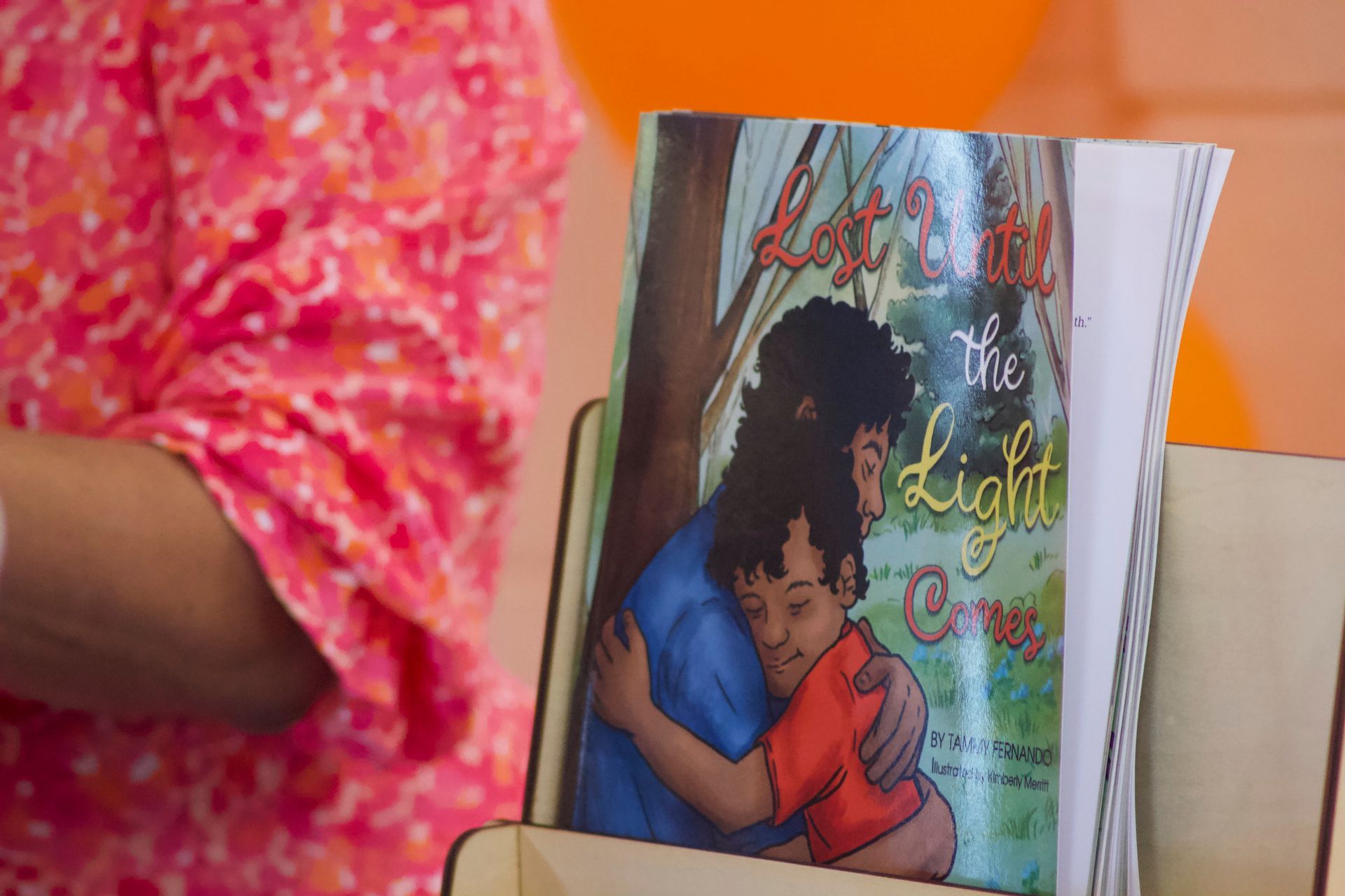A person is holding a book titled the light comes