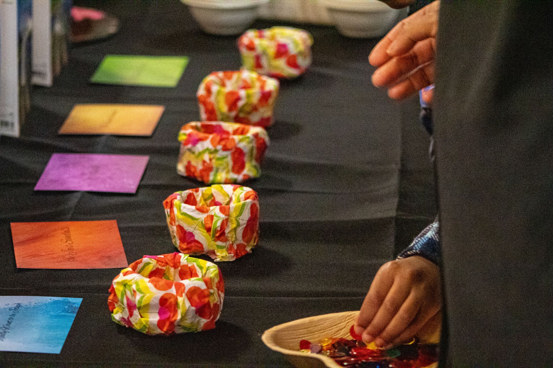 A person is putting candy in a bowl on a table.