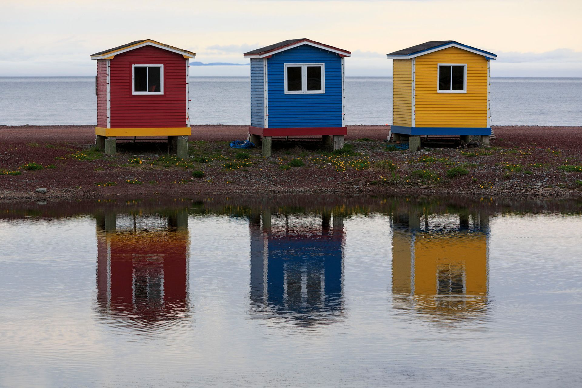 Three colorful houses are reflected in the water