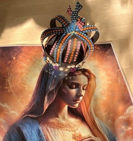 A crowned portrait of a serene woman with veil, set against a warm golden floral background.