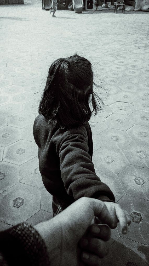Hand in hand with a child walking across a sandy beach toward the distance