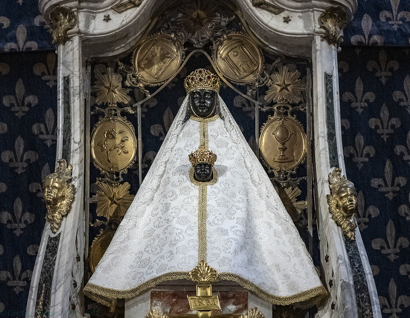 Ornate white religious vestment displayed beneath an elaborate gold altar canopy