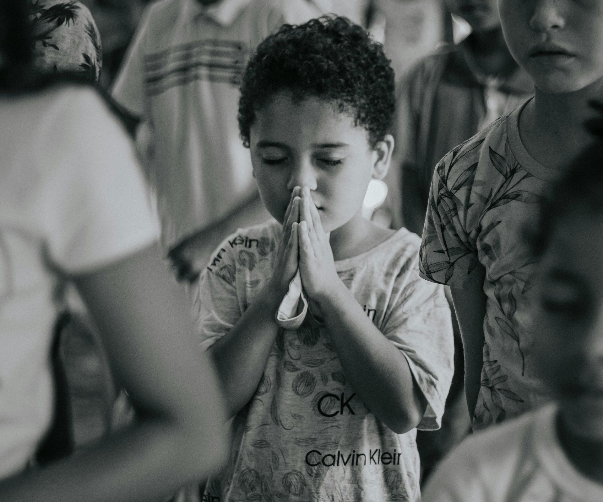 Older child kisses a baby, both on a weathered white bench in front of a red door.