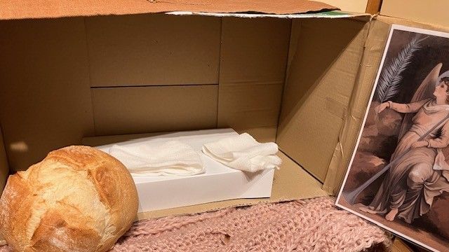 Bread roll next to a cardboard box with a box inside holding tissues and a print of an angel.