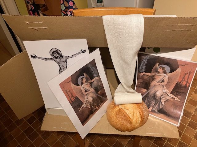 Box with religious imagery: crucified Jesus, angels, loaf of bread, and draped cloth.