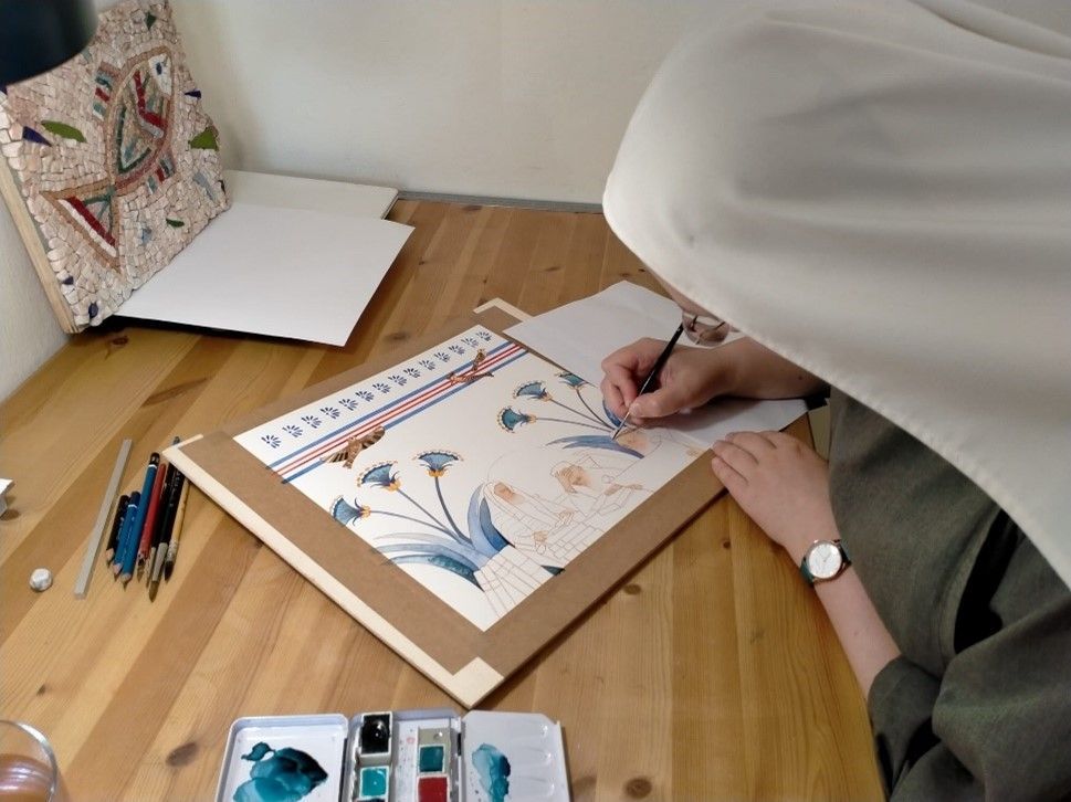 Sr. Blandine Elisabeth sitting at a wooden table, drawing on a piece of paper