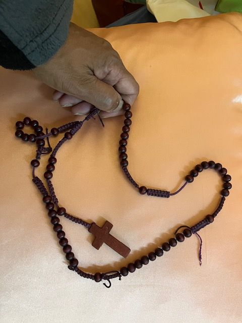 A person is holding a rosary with a cross on it