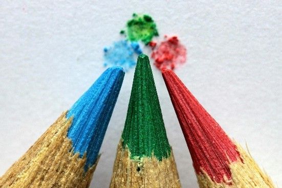 Three colored pencils: blue, green, and red, with visible color on the tips, pointing upwards.