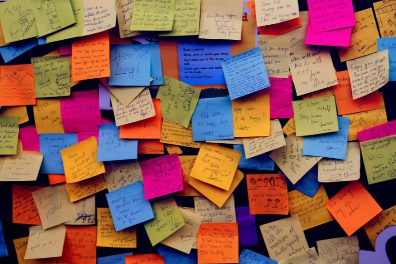 Colorful sticky notes cover a wall, each with handwritten notes.