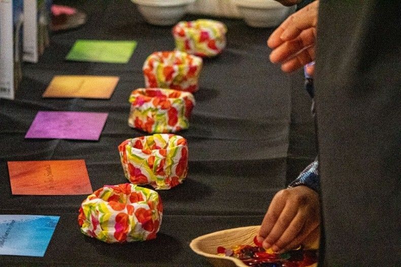 Person arranging flower petals into colorful bowls on a table with colored cards.