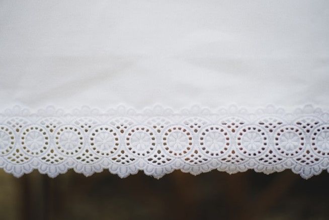 A close up of a white lace trim on a white cloth.