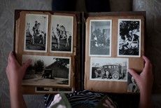 A person is holding a photo album filled with old black and white photos.