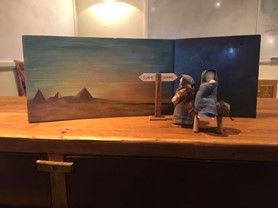 A nativity scene is sitting on a wooden table.