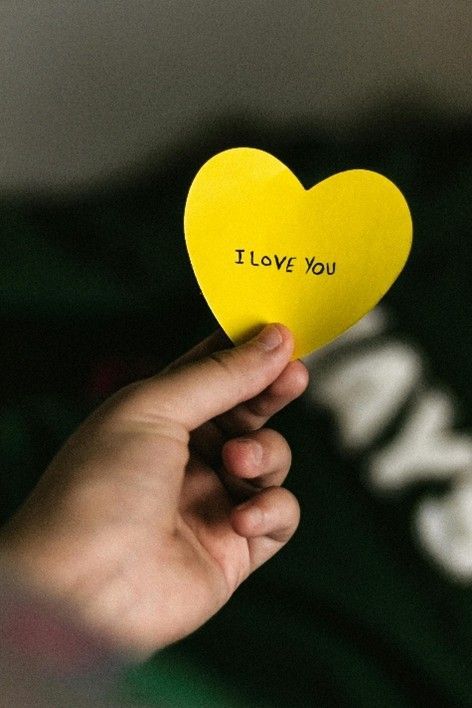 Hand holding a yellow heart-shaped paper with 