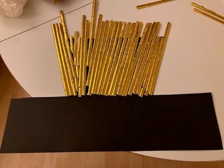 Gold rods fanned out from a black rectangular base on a light surface