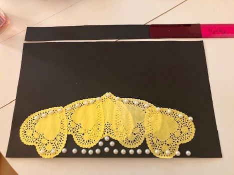 Yellow lace fan-shaped cloth with white beads on a black background