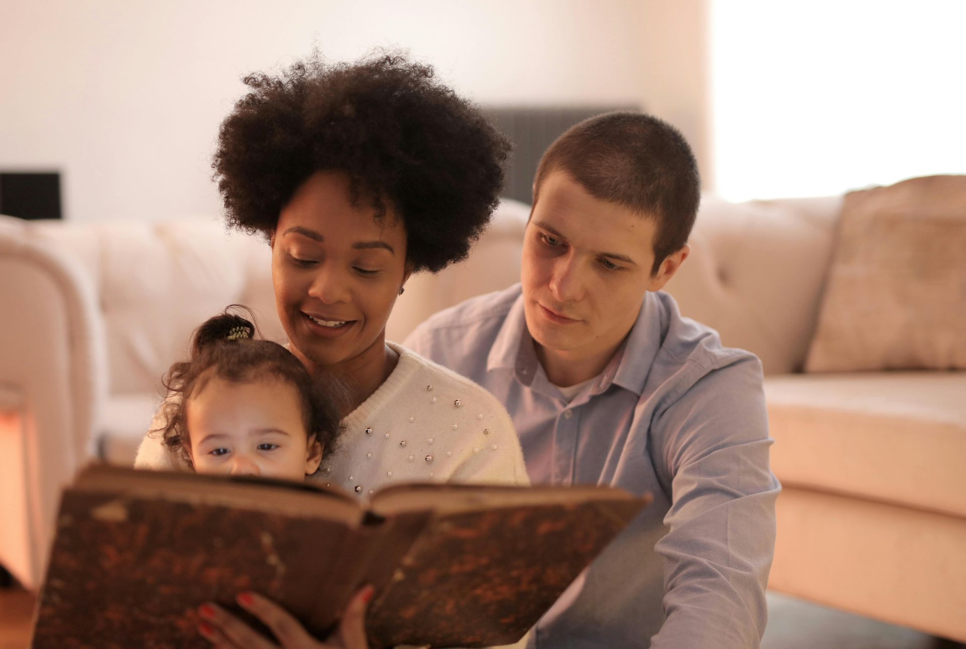 A man and woman are reading a book to a baby.