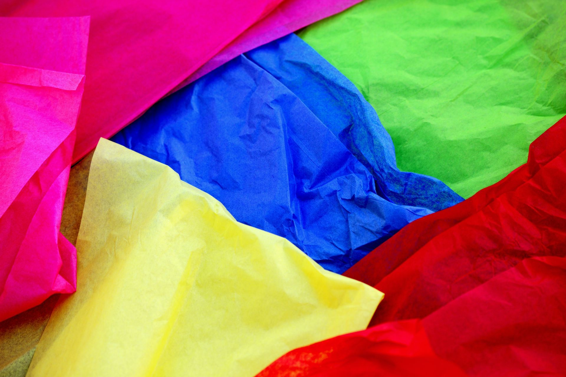 Brightly colored tissue paper, pink, green, blue, yellow, and red, crumpled and layered.