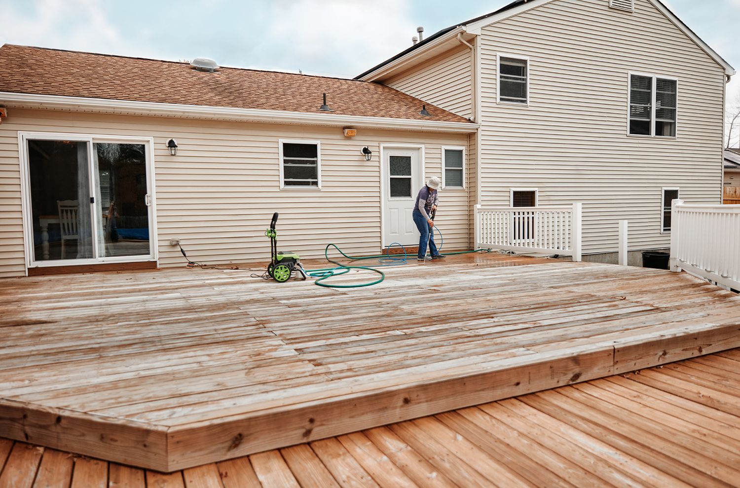 A man is standing on a wooden deck in front of a house.