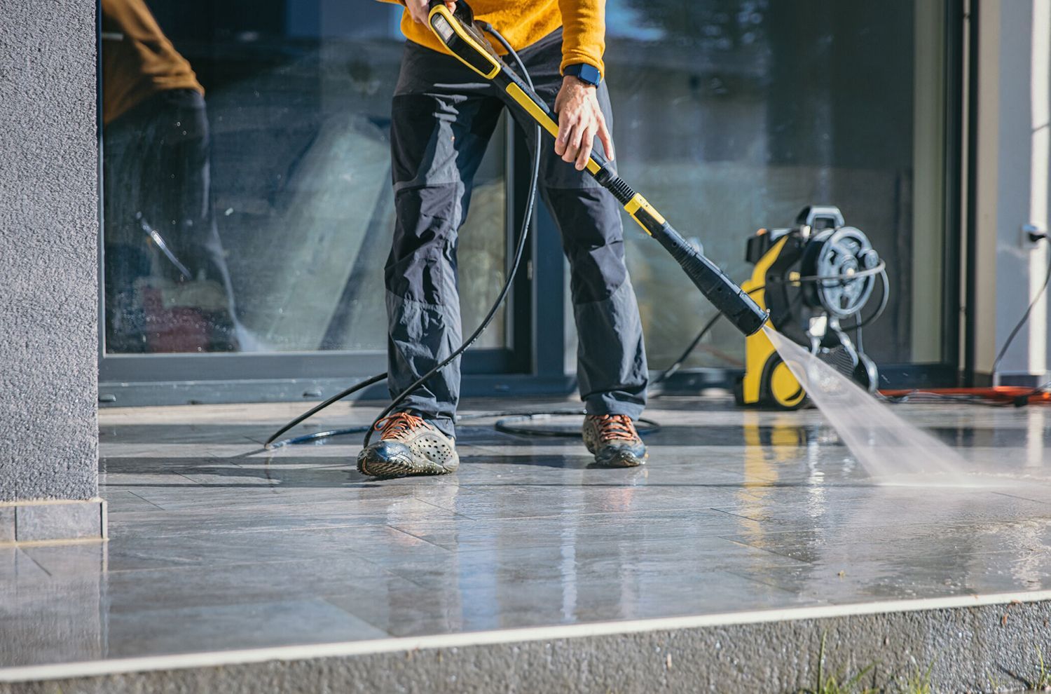A man is using a high pressure washer to clean a concrete floor.
