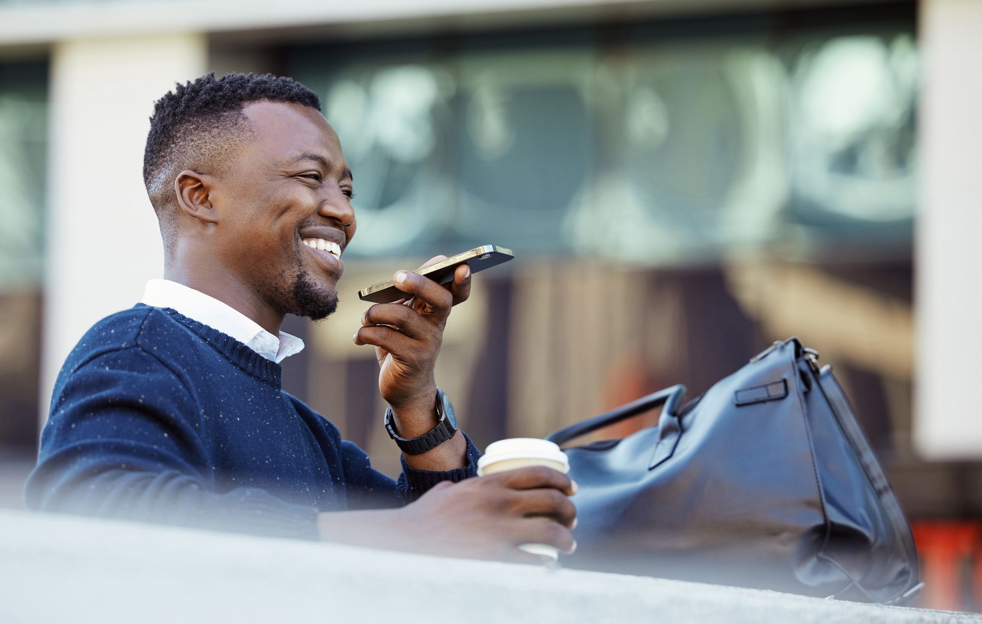 A man is talking on a cell phone while holding a cup of coffee.