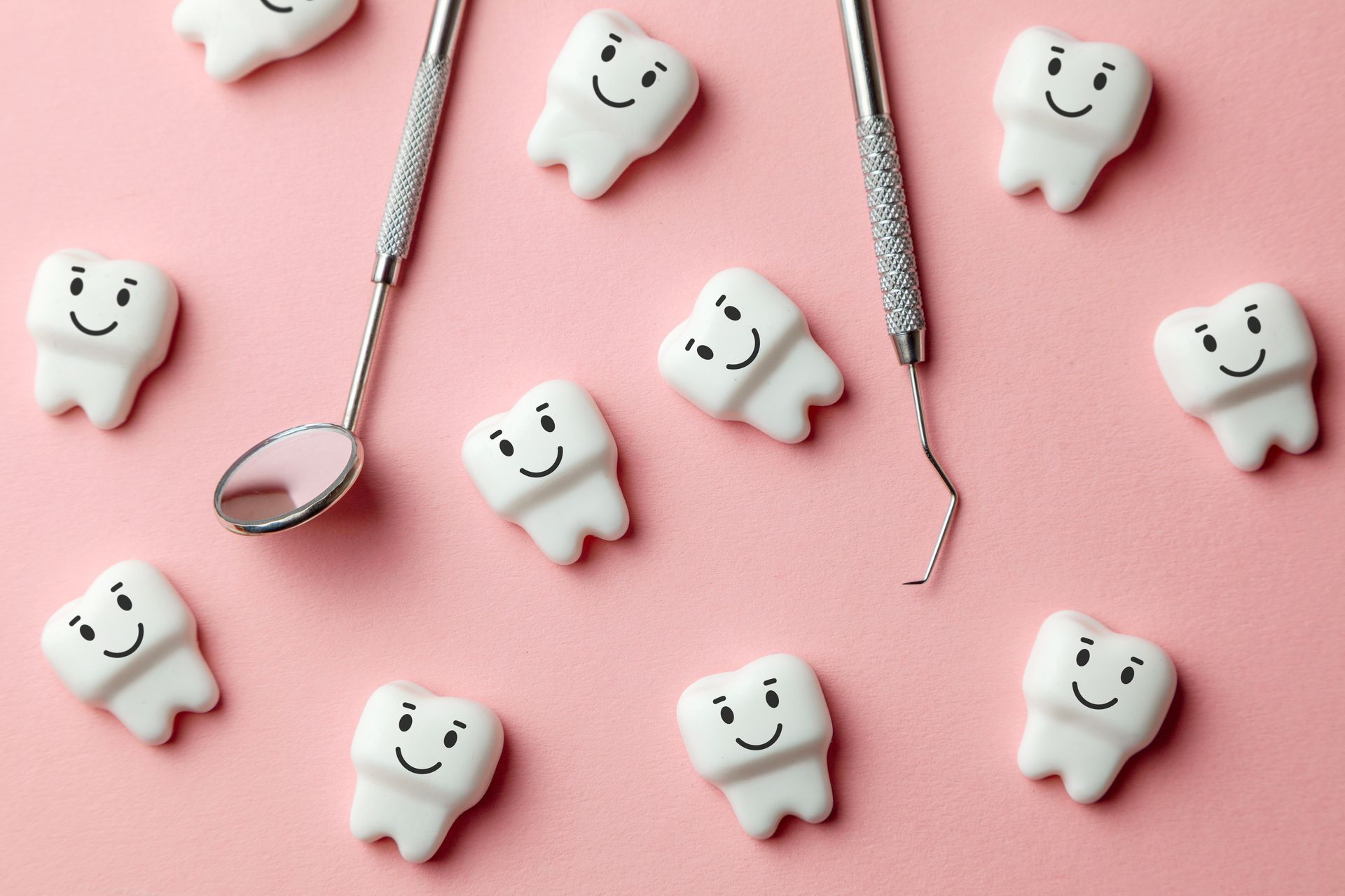 Dental tools and smiling tooth models arranged on a pink background. Dental tools and smiling tooth models arranged on a pink background.