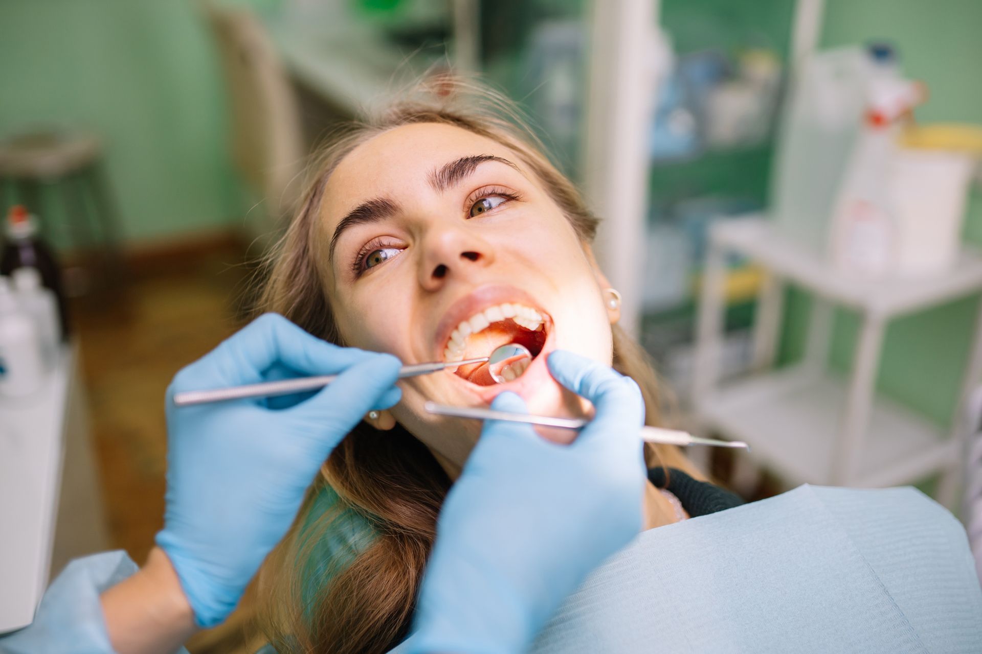Dentist examining a patient’s mouth with tools during a checkup in a dental clinic.